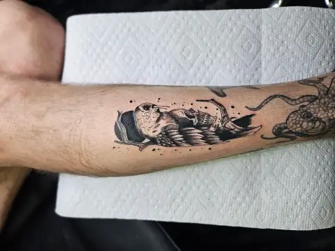 Detailed owl tattoo with wings spread and moon background in black and gray shading.