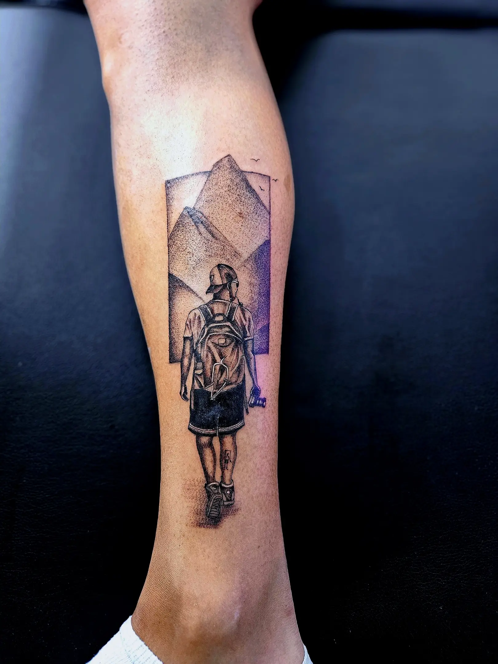 Backpacker tattoo design facing mountains, shaded with black and gray dotwork.