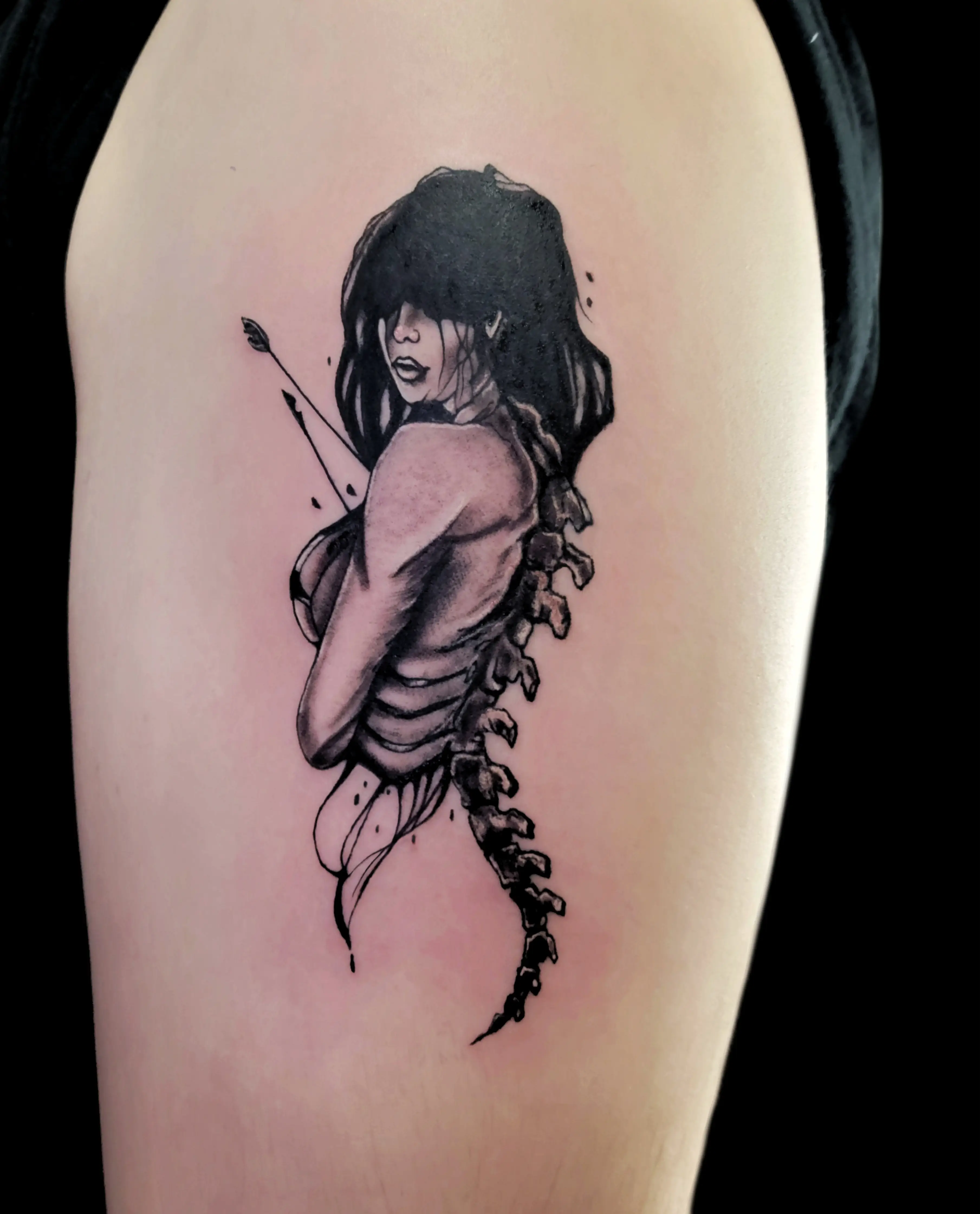 Surreal tattoo of a woman merging with a spine, shaded in black and gray.