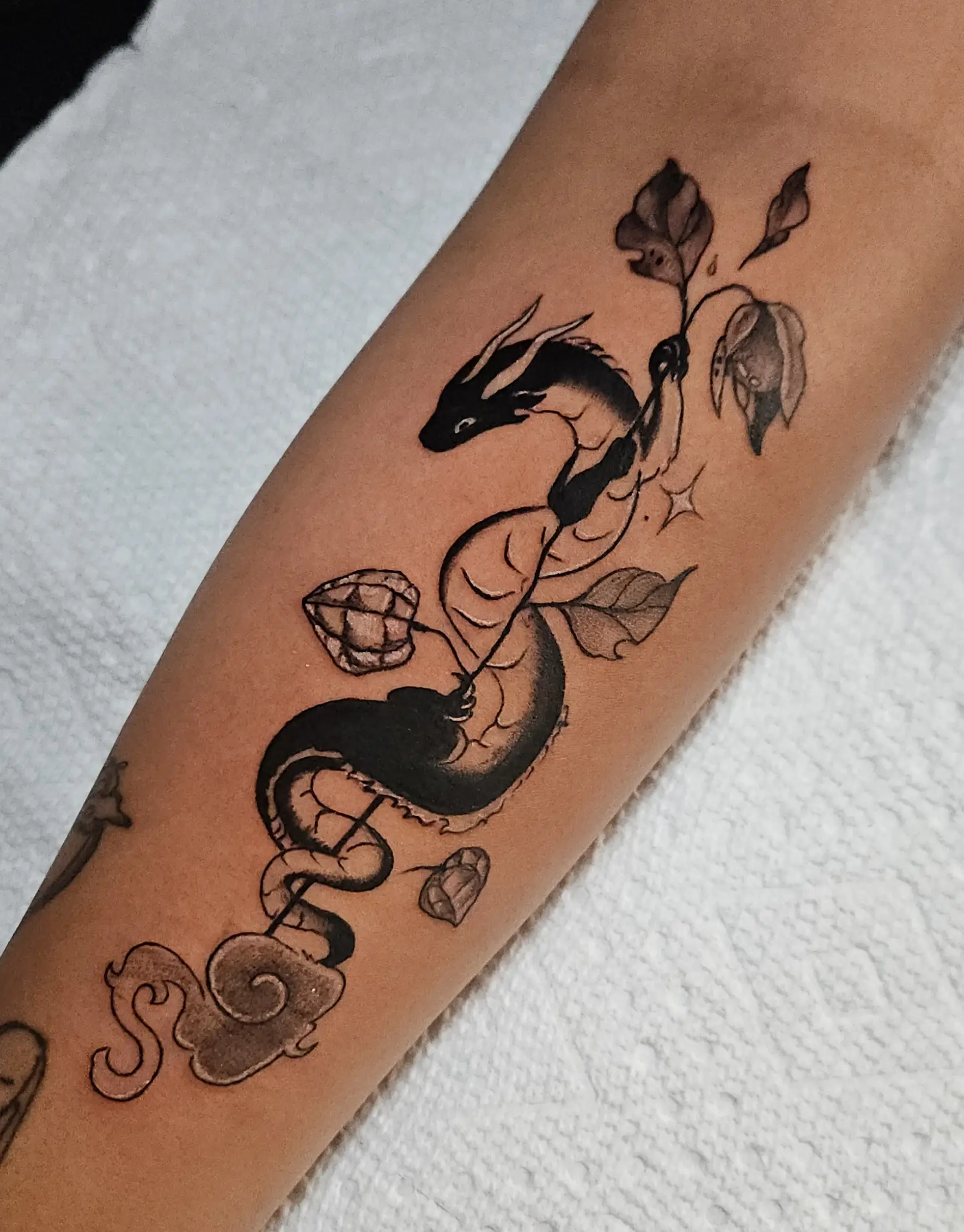 Stylized dragon entwined with leaves and abstract elements in blackwork style.