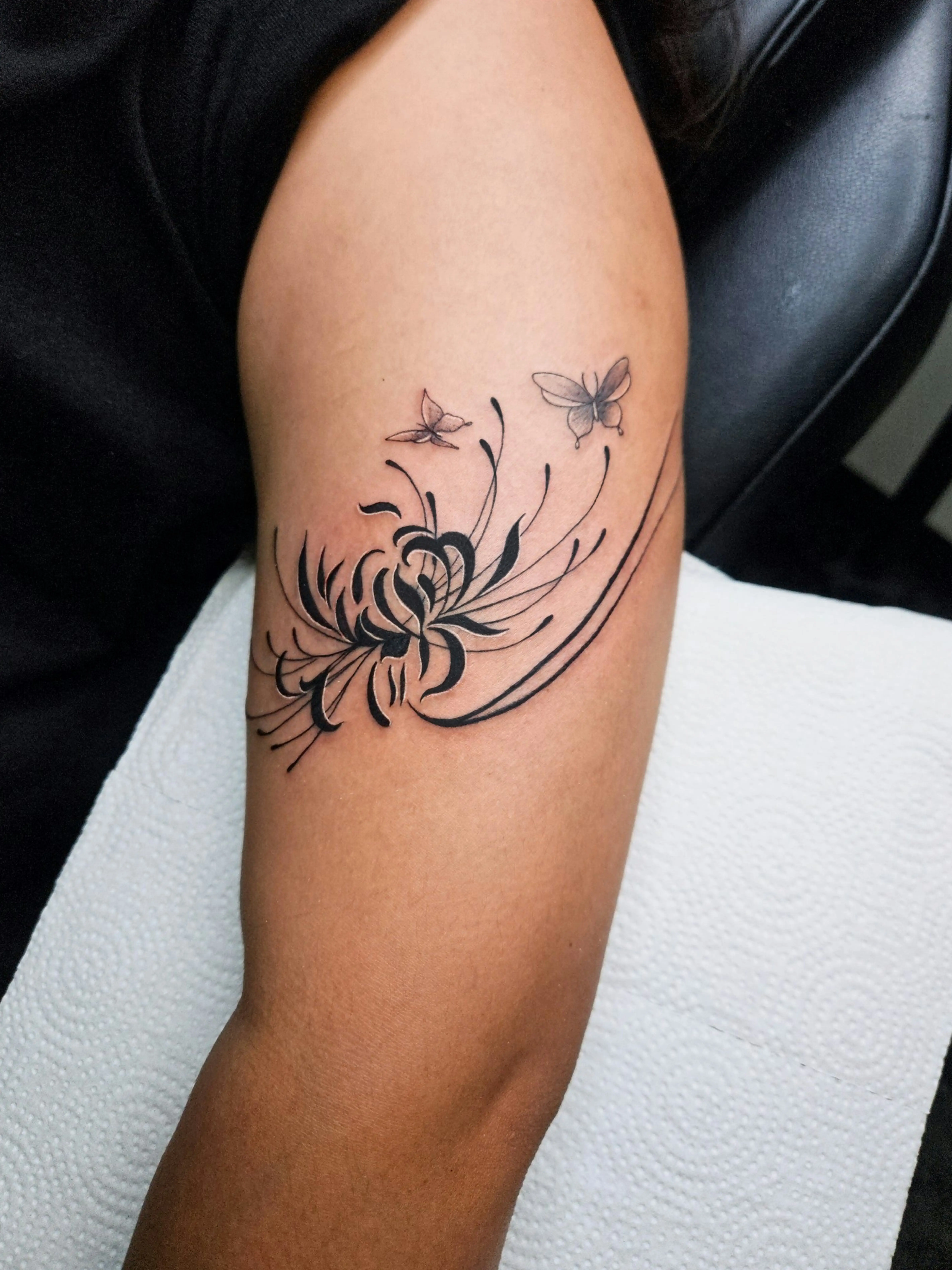 Fine line chrysanthemum tattoo with butterflies in black and gray style.
