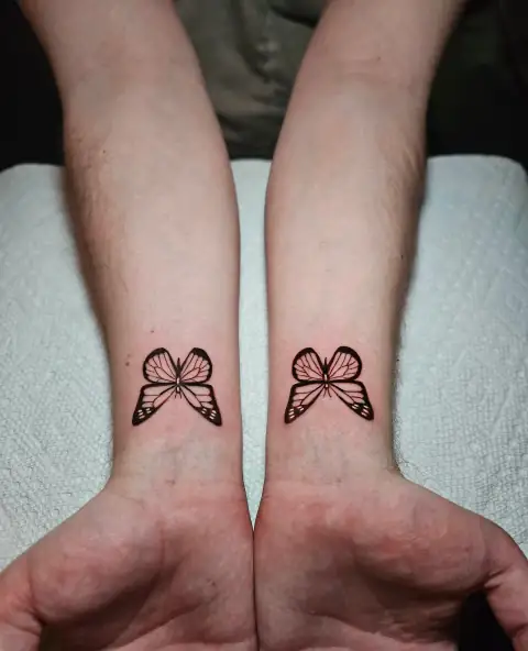 Pair of fine-line butterflies symmetrically placed on both wrists.