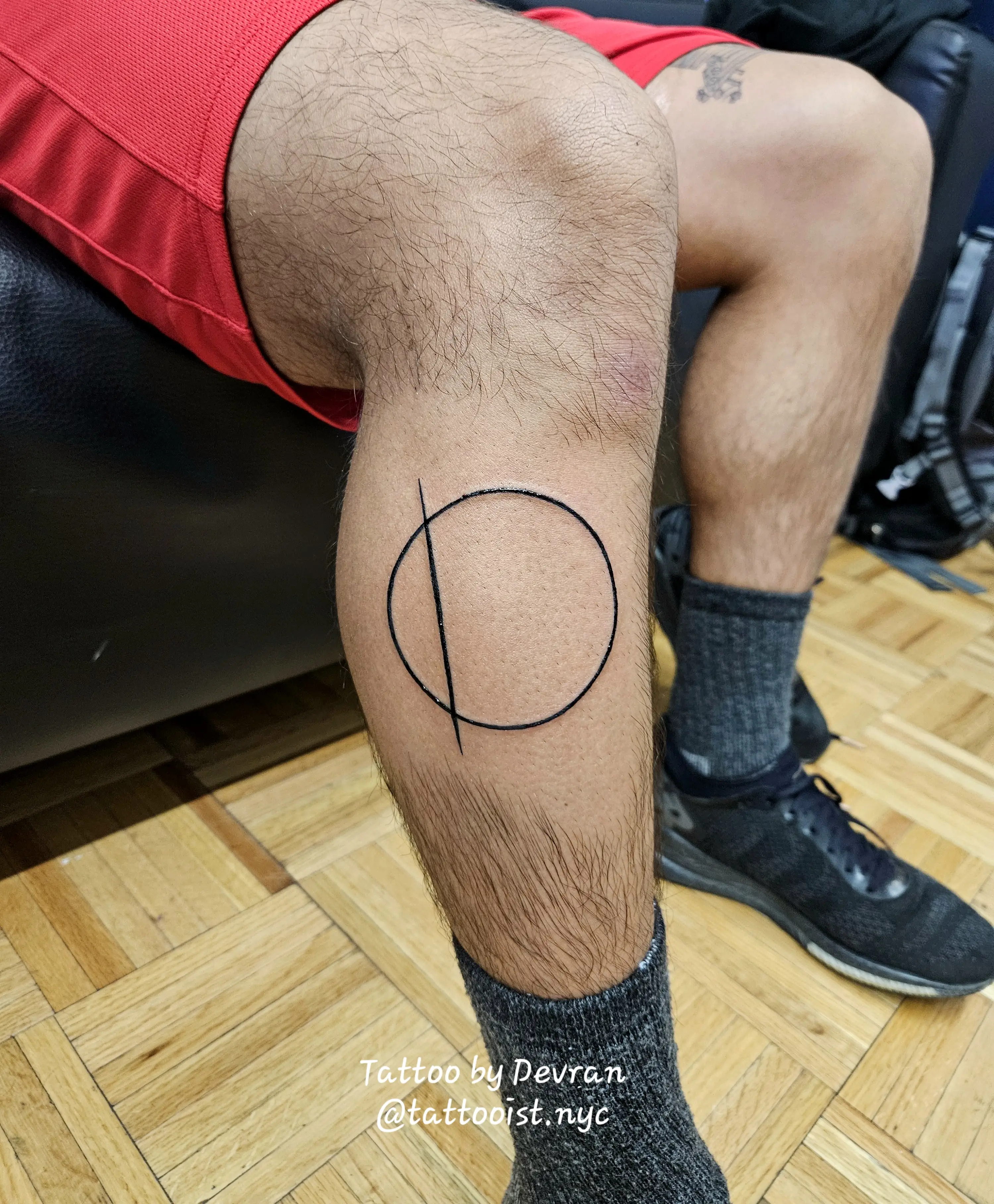 Simple geometric composition of a single line and circle cutting across the knee area.