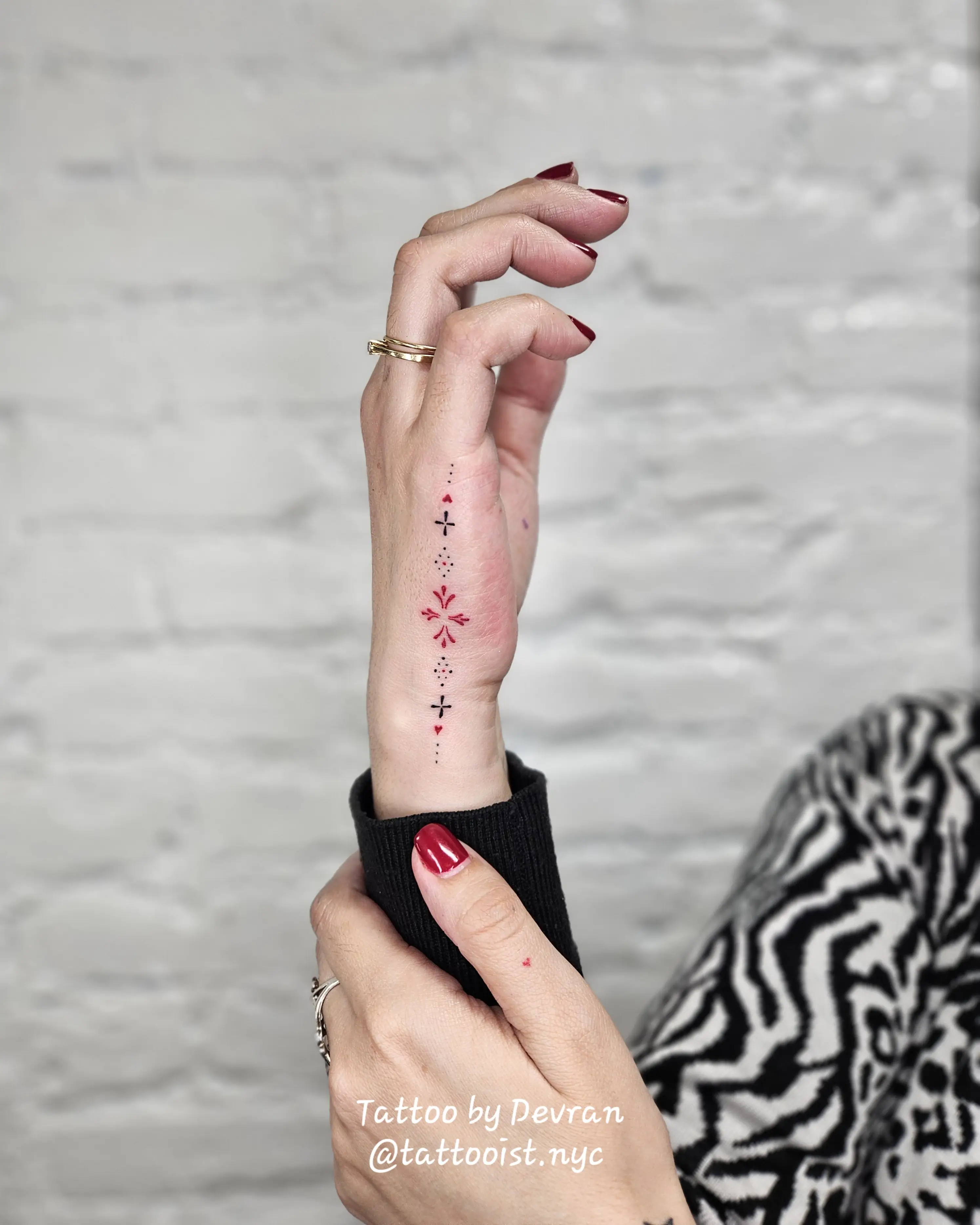 Micro ornamental arrangement on the wrist with black dot-line motifs and red accent details.