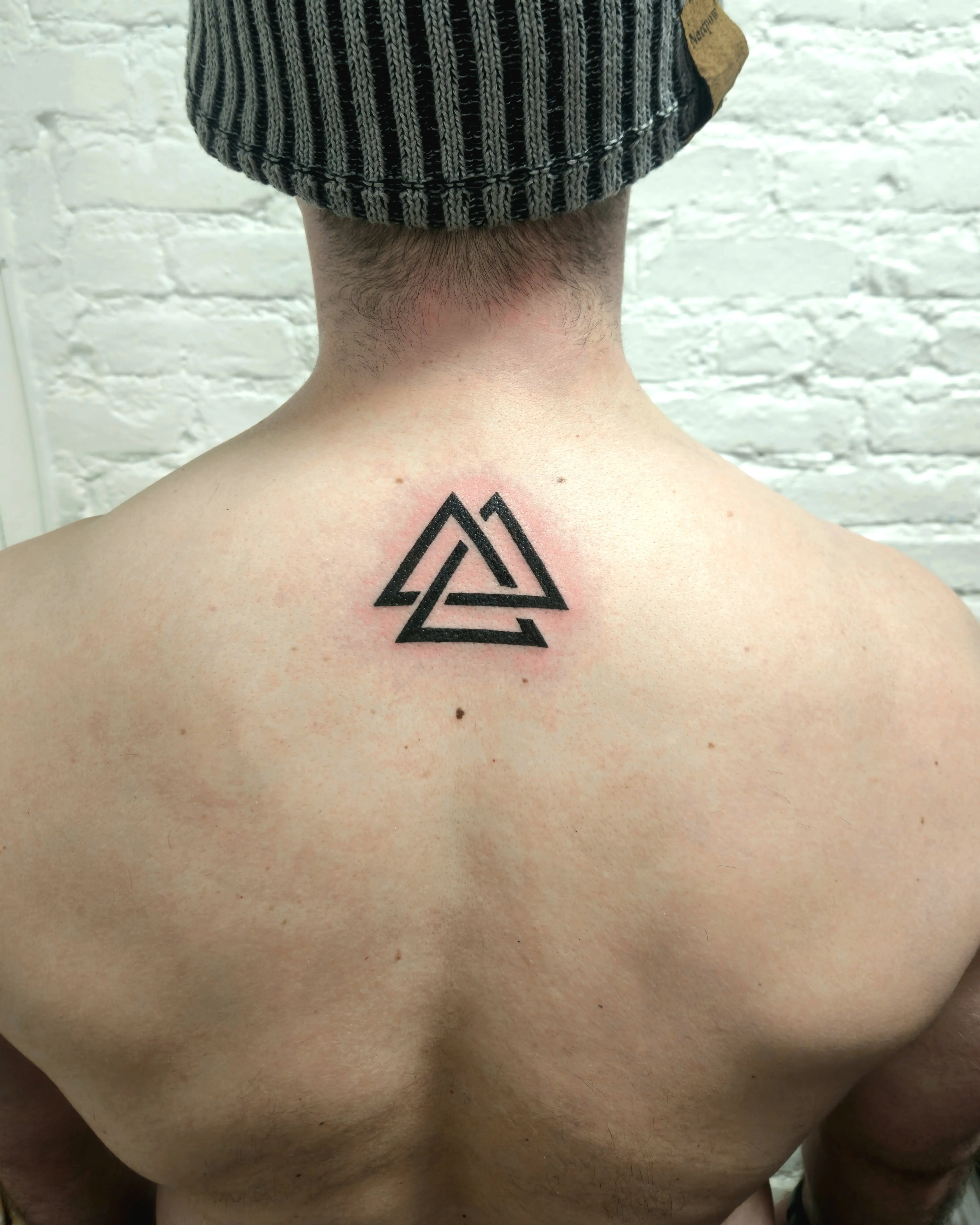 Valknut symbol composed of nested triangles placed on the upper neck; rendered with solid black lines.