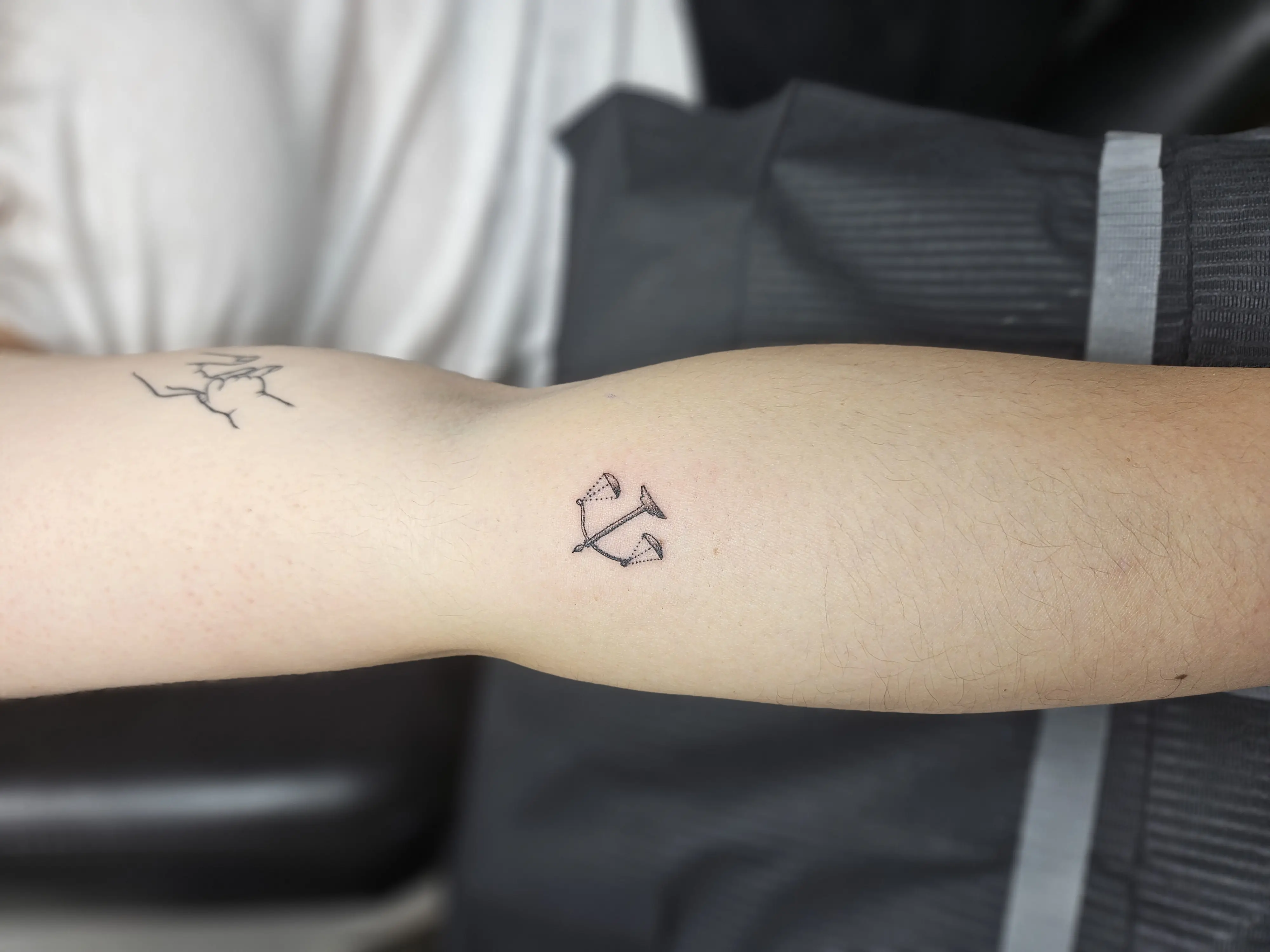 Small geometric tattoo with minimalist dotwork pattern on the inner arm.
